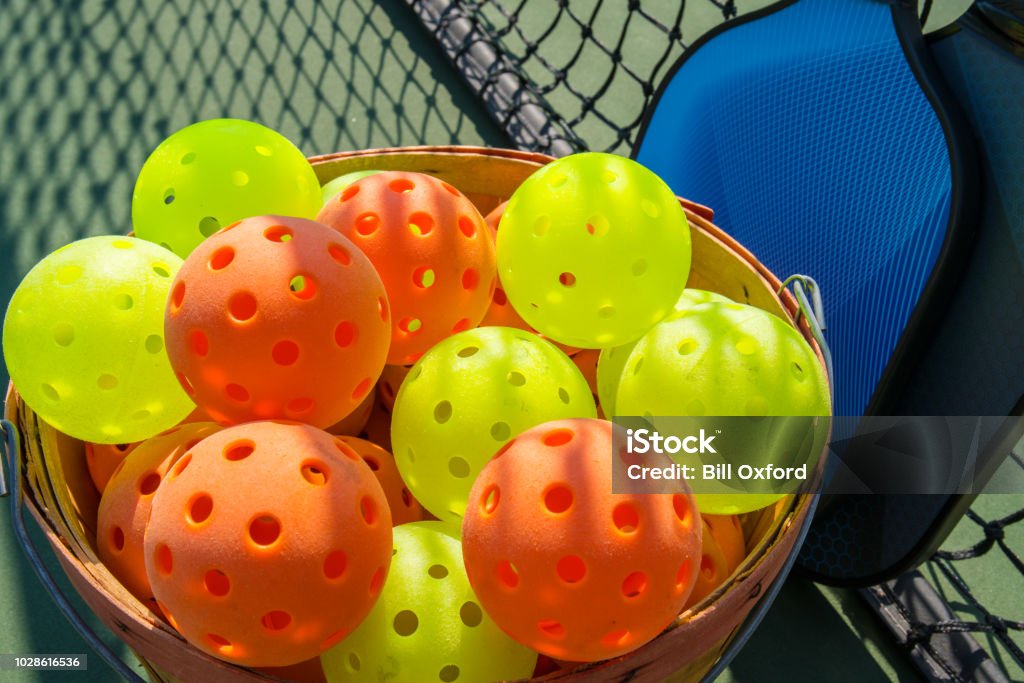 Pickleball paddles and ball on court with shadow of net ++graphics on paddles was created by photographer and is copyright free ++